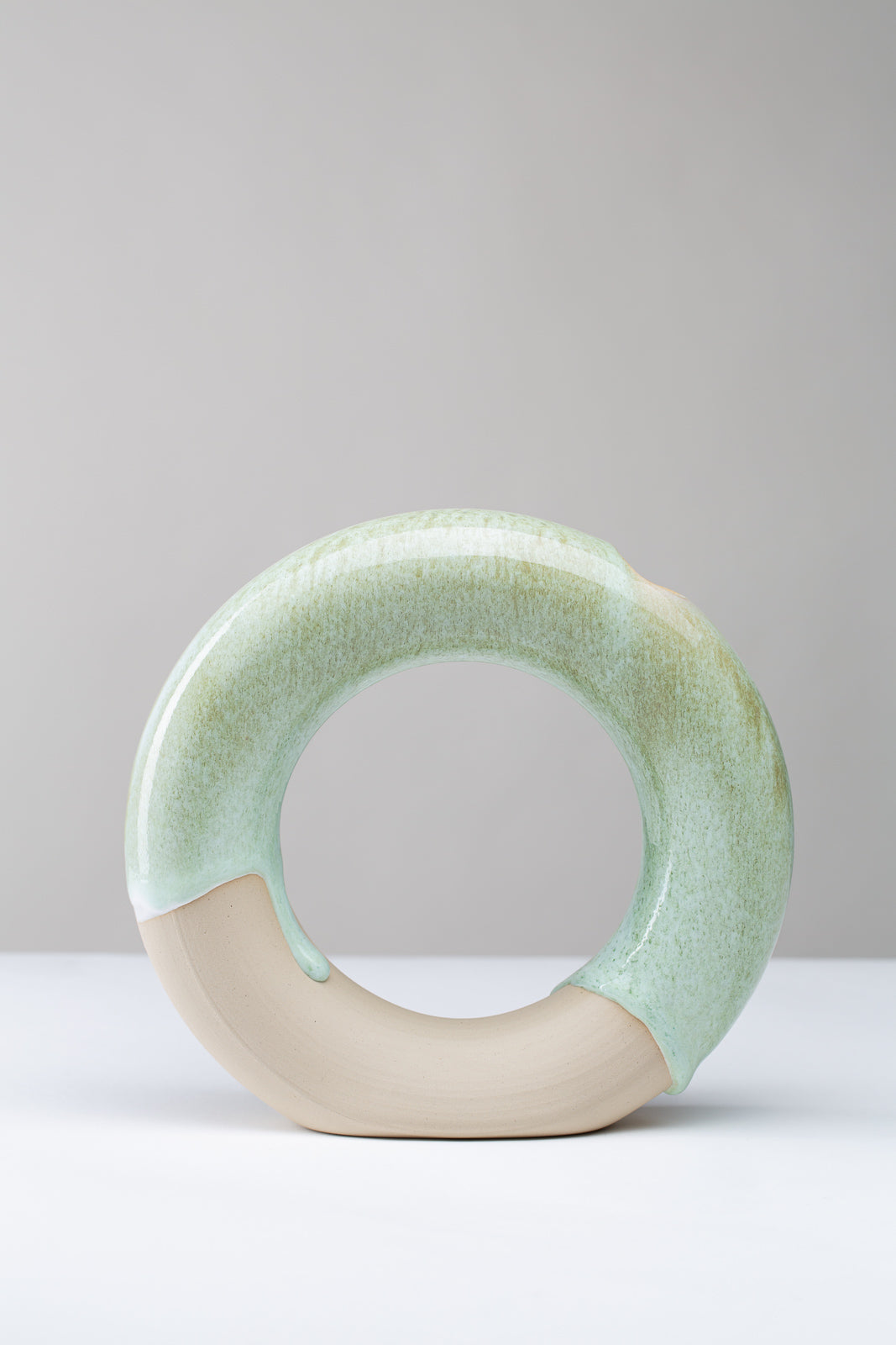runde Vase in der Form eines Ringes auf weißem Hintergrund, die Farbe der Vase sind Grüntöne, man sieht die Vase von Vorne